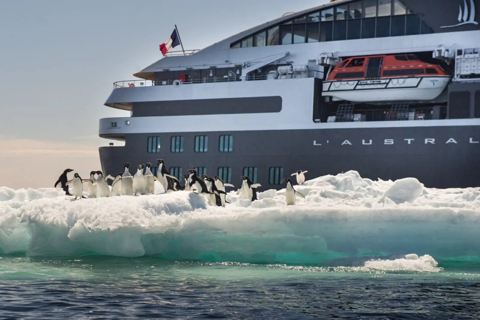 L'Austral pictured alongside a ice burg loaded with penguins